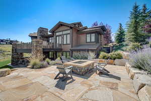 Back of property with a patio area, a wooden deck, and a fire pit