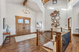 Foyer with dark hardwood / wood-style floors, high vaulted ceiling, and an inviting chandelier