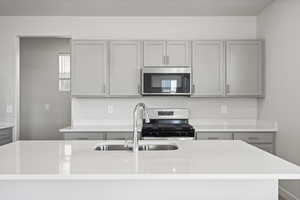 Kitchen featuring gray cabinets, a center island, appliances with stainless steel finishes, and sink