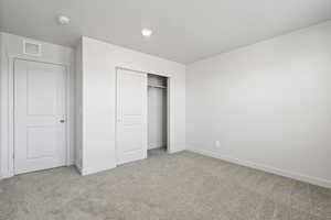 Unfurnished bedroom with light carpet and a closet