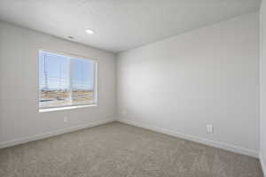 Carpeted empty room featuring a textured ceiling