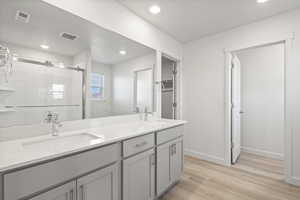 Bathroom with hardwood / wood-style flooring, vanity, and a shower with door