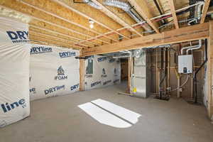 Basement with heating unit, electric panel, and tankless water heater