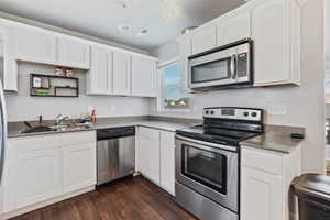 Kitchen with a stainless steel appliances, dark wood-type flooring, sink, and white cabinetry