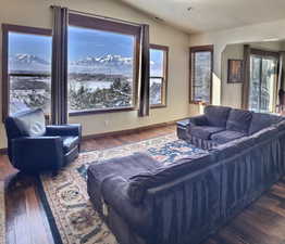 Winter view- Great room with a mountain view, dark hardwood flooring, and lofted ceiling