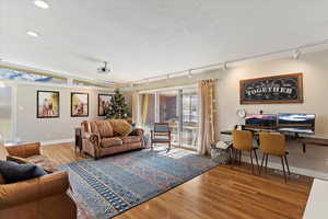 Living room with track lighting, wood-type flooring, and vaulted ceiling