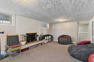 Living area featuring carpet flooring, a textured ceiling, and a brick fireplace