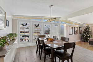 Dining space with a textured ceiling and vaulted ceiling with beams