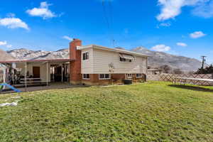 Rear view of property with a mountain view, a yard, a trampoline, and central AC unit