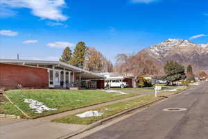 Exterior space featuring a mountain view, a front lawn, and a carport