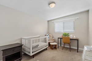 Bedroom featuring a crib, carpet floors, and vaulted ceiling