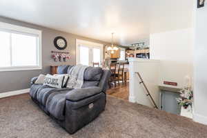 Living room featuring carpet flooring and a notable chandelier