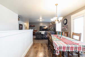 Dining space with dark hardwood / wood-style floors and an inviting chandelier