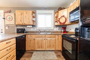 Kitchen with light brown cabinetry, sink, black appliances, and dark hardwood / wood-style flooring