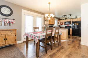 Dining room with rail lighting, an inviting chandelier, and hardwood / wood-style flooring