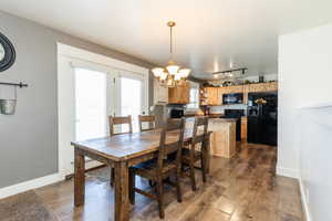 Dining area with track lighting, baseboards, a chandelier, and dark wood finished floors