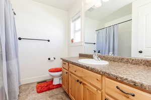 Full bath with visible vents, a shower with shower curtain, baseboards, toilet, and vanity
