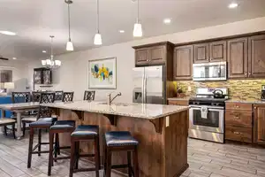 Kitchen with a center island with sink, a kitchen breakfast bar, sink, appliances with stainless steel finishes, and decorative light fixtures