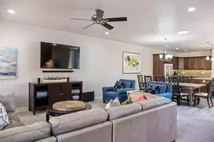 Living room featuring ceiling fan with notable chandelier