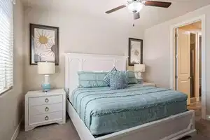 Bedroom with ceiling fan, light carpet, and multiple windows