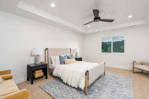 Carpeted bedroom featuring a tray ceiling, ceiling fan, and wood ceiling