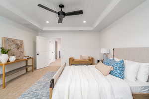 Bedroom featuring a raised ceiling, ceiling fan, crown molding, and light carpet