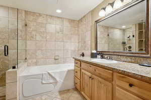 Bathroom with tile patterned flooring, vanity, shower with separate bathtub, and tile walls