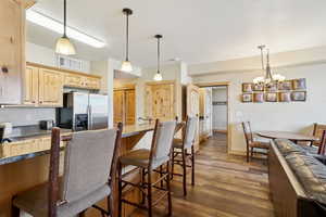 Kitchen with stainless steel fridge with ice dispenser, dark hardwood / wood-style flooring, a notable chandelier, pendant lighting, and light brown cabinetry