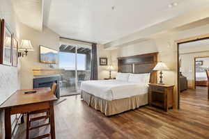 Bedroom featuring access to exterior, dark hardwood / wood-style flooring, and a tile fireplace