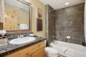 Full bathroom with tiled shower / bath combo, toilet, and vanity