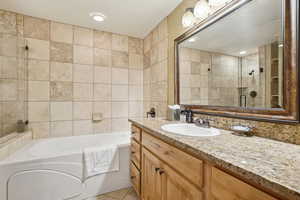 Bathroom with tile patterned floors, vanity, and separate shower and tub