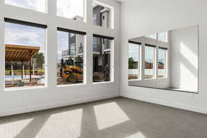 Carpeted empty room featuring a high ceiling and plenty of natural light