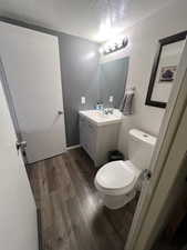 Bathroom with hardwood / wood-style floors, vanity, a textured ceiling, and toilet