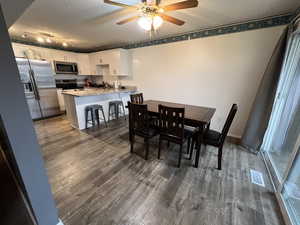 Dining room featuring dark hardwood / wood-style flooring, a textured ceiling, and ceiling fan