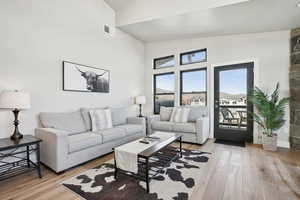 Living room with light hardwood / wood-style floors and vaulted ceiling