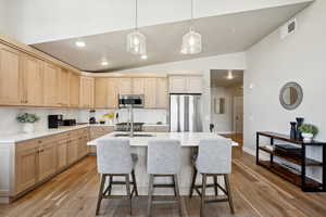 Kitchen featuring lofted ceiling, sink, light wood-type flooring, light brown cabinetry, and stainless steel appliances