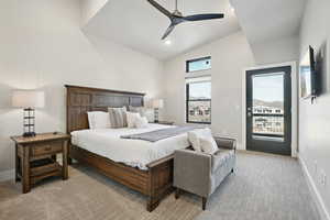 Carpeted bedroom featuring access to exterior, vaulted ceiling, and ceiling fan