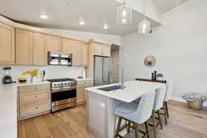 Kitchen with pendant lighting, premium appliances, sink, and vaulted ceiling