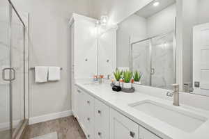 Bathroom with hardwood / wood-style flooring, vanity, and a shower with shower door