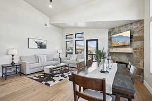 Living room featuring high vaulted ceiling, light hardwood / wood-style floors, and a stone fireplace