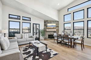 Living room featuring a mountain view, light wood-type flooring, high vaulted ceiling, and a stone fireplace