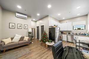 Kitchen featuring white cabinetry, light wood-type flooring, an AC wall unit, and appliances with stainless steel finishes