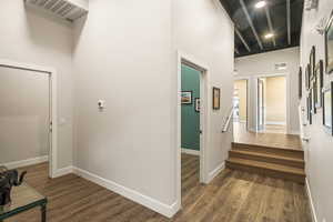 Hall featuring a towering ceiling and dark wood-type flooring