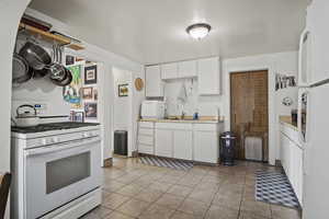 Kitchen with white cabinetry, white appliances, and light tile patterned floors