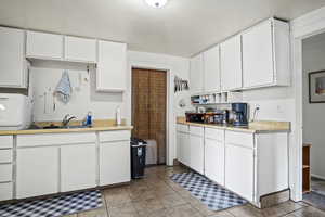 Kitchen with white cabinetry, sink, and light tile patterned floors