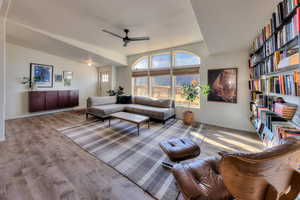 Living room with ceiling fan, vaulted ceiling, and light hardwood / wood-style flooring