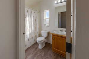 Bathroom with walk in shower, toilet, vanity, and hardwood / wood-style flooring