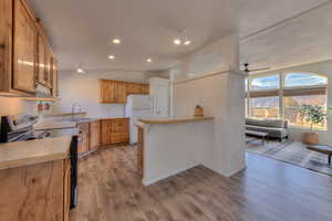 Kitchen with light wood-type flooring, ceiling fan, sink, electric stove, and white fridge