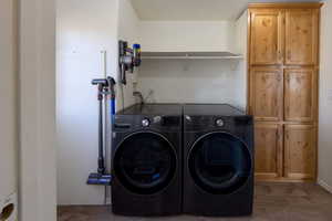 Laundry room with washing machine and clothes dryer, dark hardwood / wood-style flooring, and cabinets