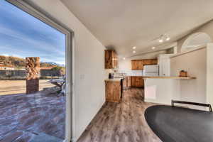 Kitchen featuring kitchen peninsula, vaulted ceiling, dark wood-type flooring, white fridge, and stainless steel electric range oven